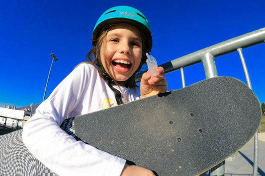 An image shows a little skateboarder holding a mouth guard