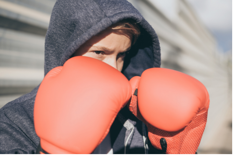 Close-up of a young boxer wearing red gloves, preparing for a fight.