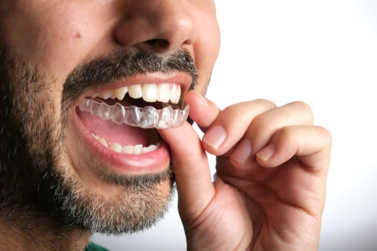 A bearded man applying clear aligners