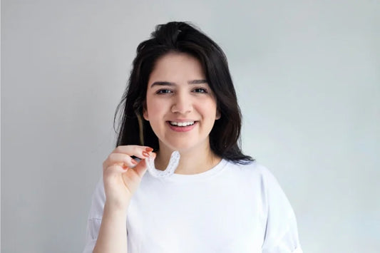 A girl smiling and holding a mouth guard