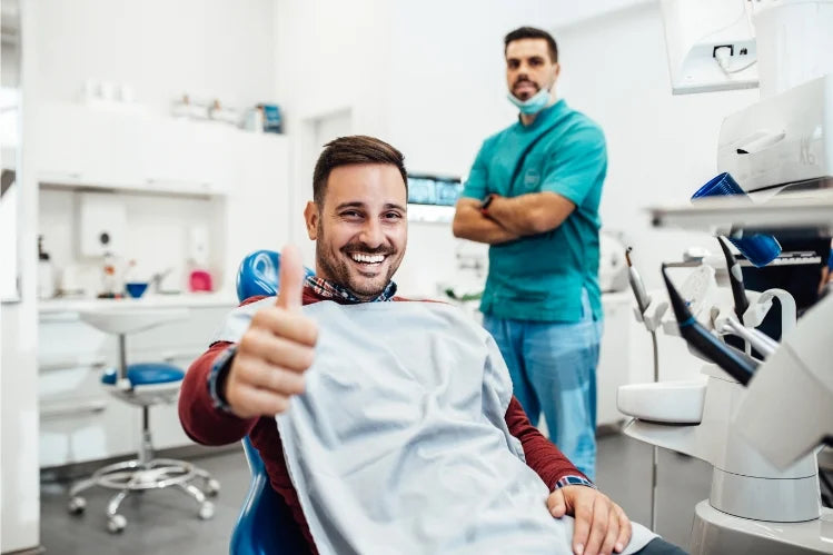 A man giving a thumbs up sign while sitting in a dentist’s office