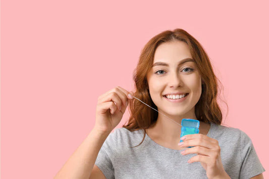 A young girl with a perfect smile, holding a dental floss.