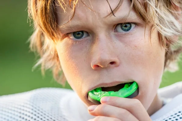 Boy inserting a mouth guard for teeth protection before playing sports.