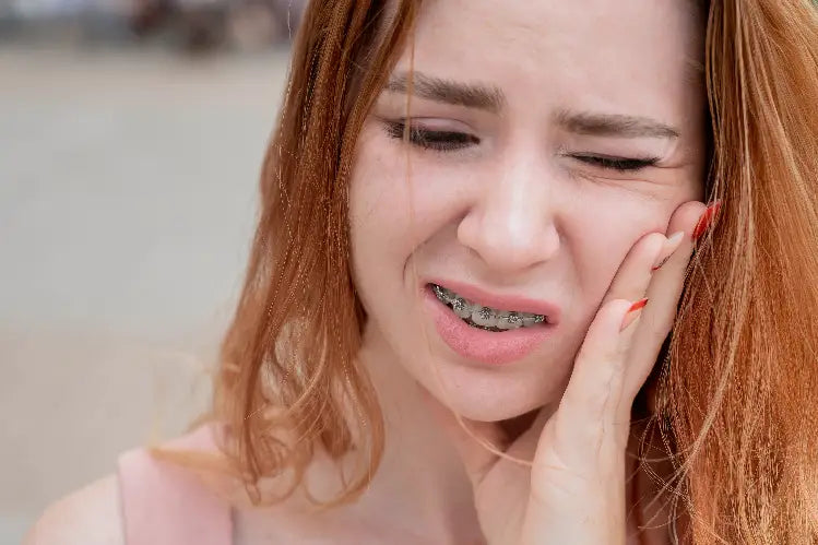 An image of a girl with a toothache due to her braces