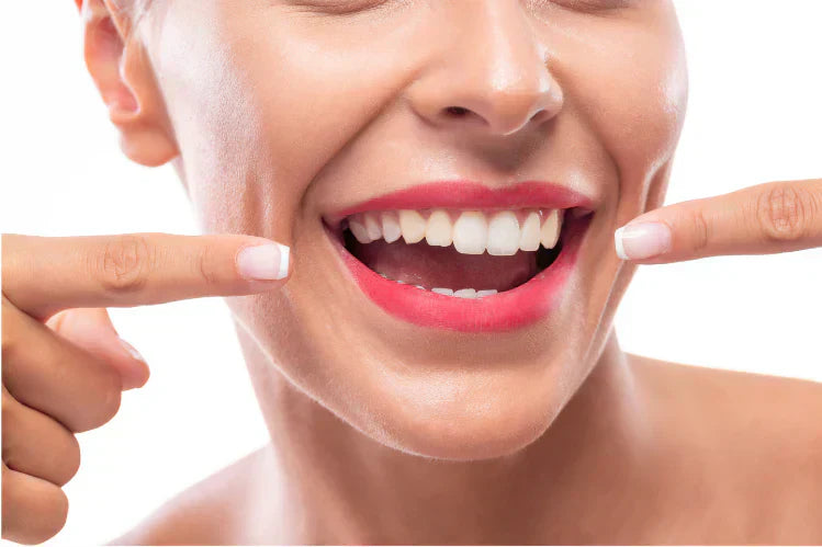 A person smiling to show their straight teeth while pointing at them