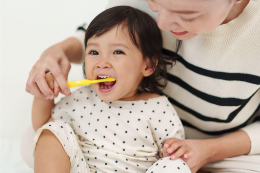 A mother brushing a toddler's teeth